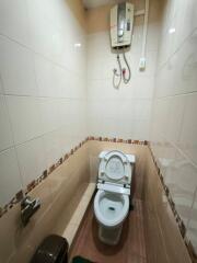 Compact bathroom with tiled walls and electric water heater