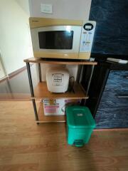Compact kitchen corner with microwave, rice cooker, and trash bin