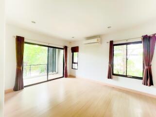 Spacious and brightly lit living room with large windows and wooden flooring