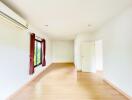 Spacious and well-lit empty bedroom with wooden flooring