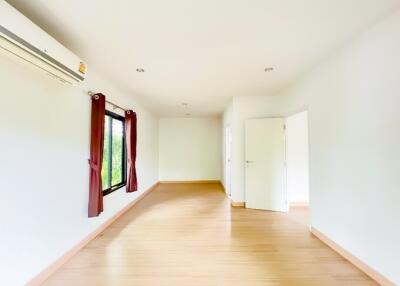 Spacious and well-lit empty bedroom with wooden flooring