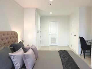 Modern bedroom interior with a neatly made bed and a glimpse of an office space