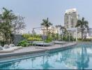 Luxury outdoor swimming pool with lounge chairs and cityscape backdrop