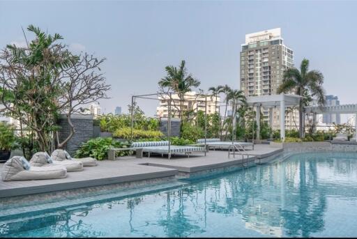 Luxury outdoor swimming pool with lounge chairs and cityscape backdrop