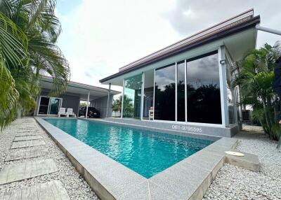 Modern house with pool and large windows surrounded by tropical plants
