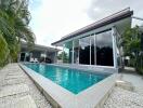 Modern house with pool and large windows surrounded by tropical plants