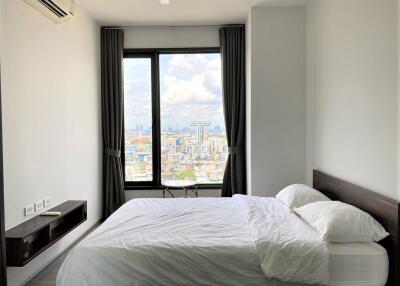 Clean and modern bedroom with a large window offering a city view