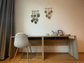 Cozy bedroom with a modern writing desk, decorative wall hangings, and wooden flooring