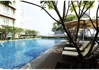 A luxurious outdoor swimming pool area with loungers and cityscape