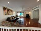 Spacious living room with hardwood floors, artistic wall decor, and ample natural light