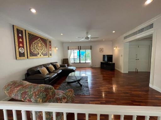 Spacious living room with hardwood floors, artistic wall decor, and ample natural light