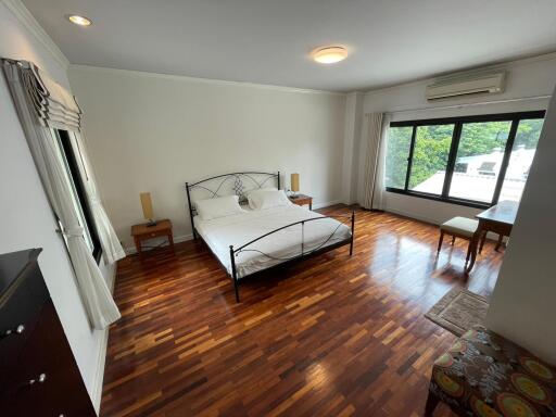 Spacious bedroom with wooden flooring and large window