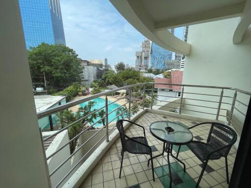 Spacious balcony with seating overlooking a pool and cityscape