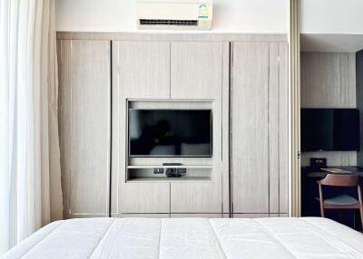 Modern bedroom with built-in wooden wardrobe and television