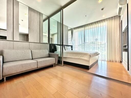 Modern studio apartment bedroom with combined living space, ample natural light, and hardwood floors