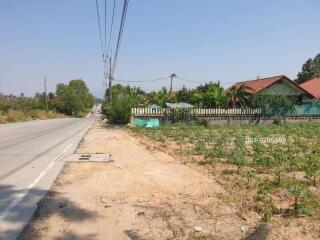 Spacious land area near a paved road with potential for property development, adjacent to residential buildings