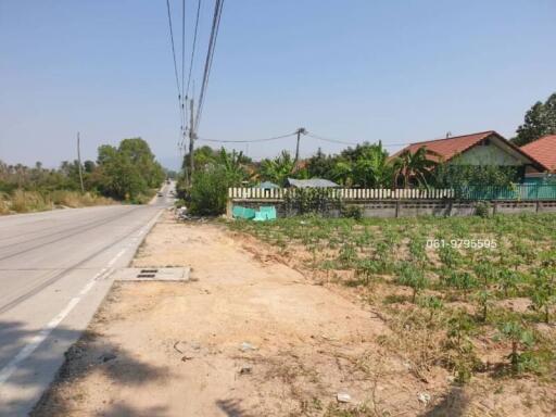 Spacious land area near a paved road with potential for property development, adjacent to residential buildings