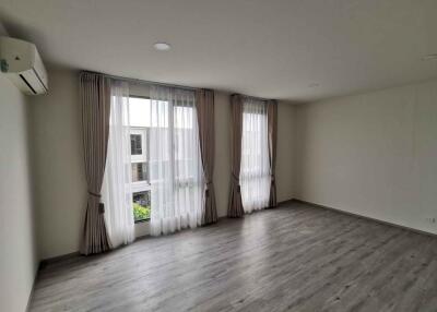 Spacious empty living room with large windows and light curtains