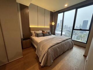 Cozy bedroom with floor-to-ceiling windows offering a city view