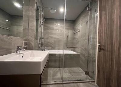 Modern bathroom with glass shower enclosure and grey tiles