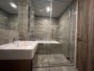 Modern bathroom with glass shower enclosure and grey tiles