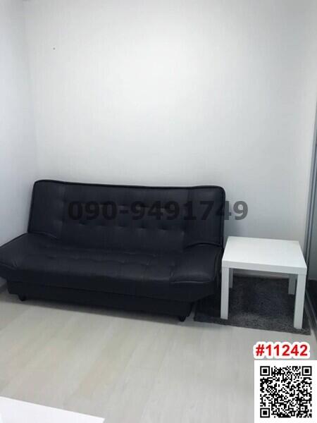 Small living room with a black sofa and white side table