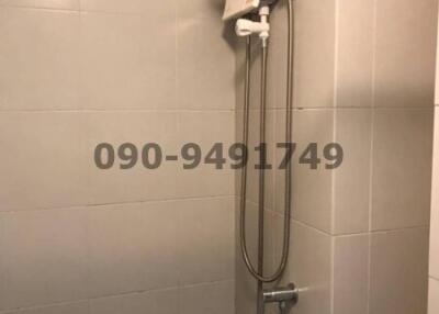 Electric shower unit with hand-held shower head in a tiled bathroom