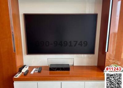 Modern living room with large wall-mounted television and white cabinetry