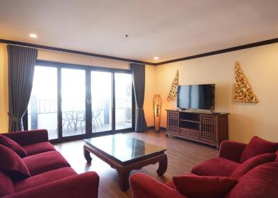 Spacious living room with red sofas and a large window leading to a balcony