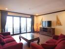 Spacious living room with red sofas and a large window leading to a balcony