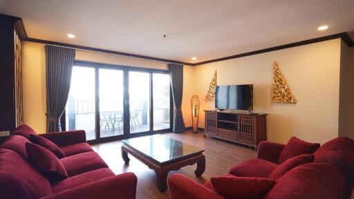 Spacious living room with red sofas and a large window leading to a balcony