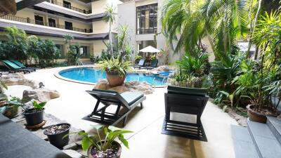 Tropical resort-style pool area with sun loungers and lush greenery