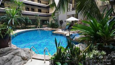 Residential building with a central swimming pool surrounded by greenery and lounge area