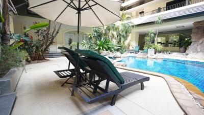 Spacious outdoor pool area with sun loungers and large umbrella