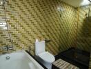 Modern bathroom with golden tile walls, a bathtub, and a glass shower