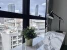 Home office with city view, desk lamp, and plant on a marble top desk