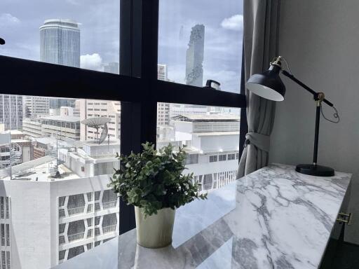 Home office with city view, desk lamp, and plant on a marble top desk