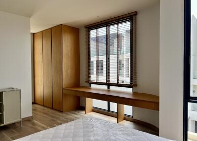Modern bedroom with large window and built-in wooden wardrobe