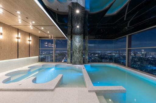 Luxurious indoor swimming pool with city view at nighttime