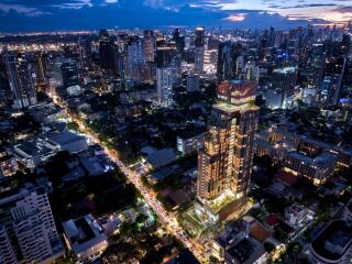 Aerial view of a well-lit modern high-rise building in an urban setting at dusk