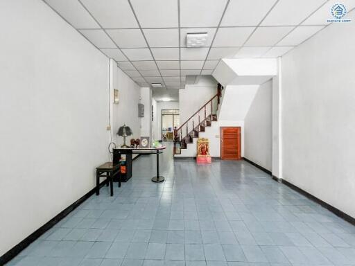 Spacious hallway with blue tiled flooring and staircase