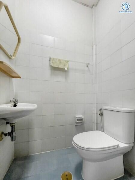Compact white-tiled bathroom with toilet and sink