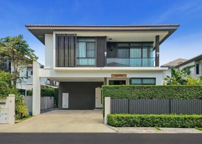 Modern two-storey house with lush greenery and a spacious driveway