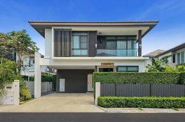 Modern two-storey house with lush greenery and a spacious driveway