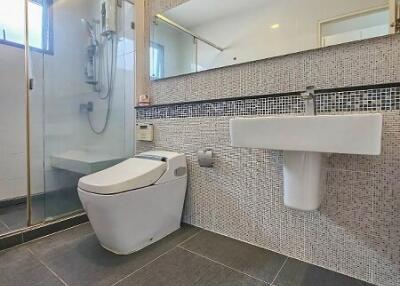 Modern bathroom with mosaic tiled walls, walk-in shower, and porcelain fixtures