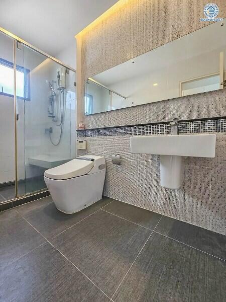 Modern bathroom with mosaic tiled walls, walk-in shower, and porcelain fixtures