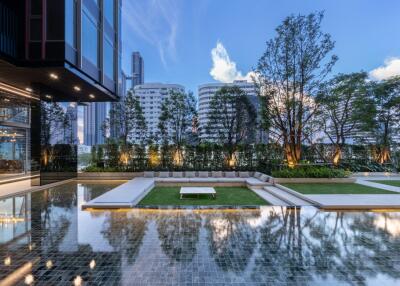 Modern apartment complex with pool and landscaped garden against a city skyline