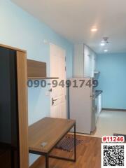 Compact entryway inside a building with refrigerator and wooden furniture