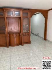 Spacious living room with built-in wooden cabinets and tiled flooring