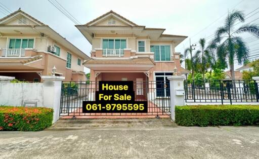 Spacious two-story house for sale with a gate and a clear sky in the background